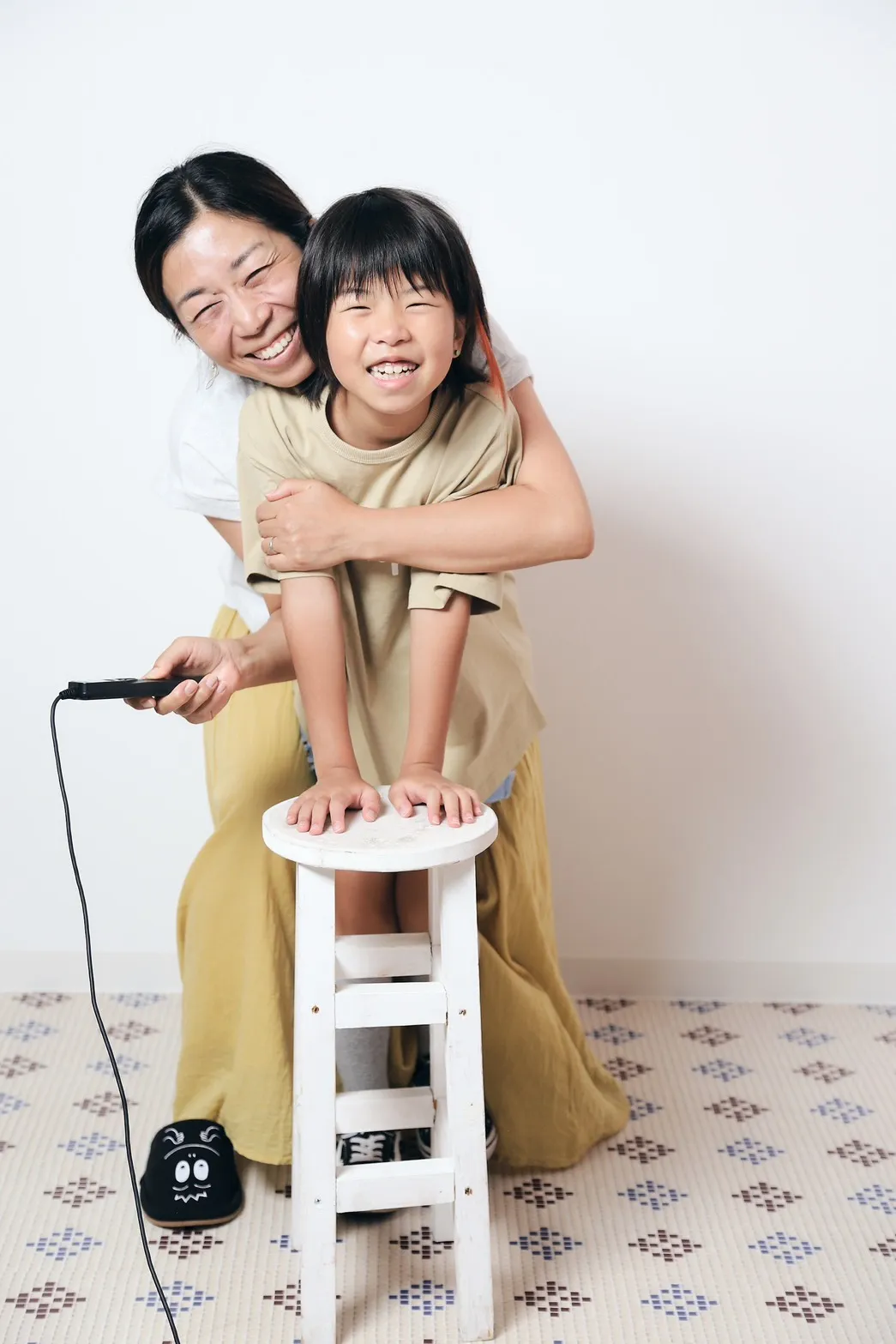 笑顔の奈那さんと娘さん。手にはシャッターのリモコン、足元はスリッパ